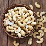 Bowl of halved cashew nuts in a wooden bowl